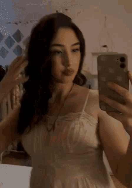 a woman in a white dress is taking a selfie with her phone .