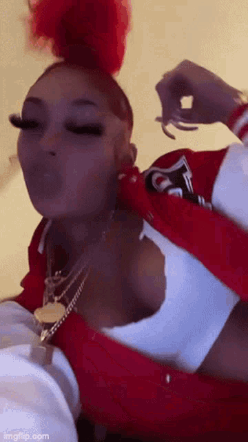 a woman wearing a red jacket and a white tank top is blowing a bubble .