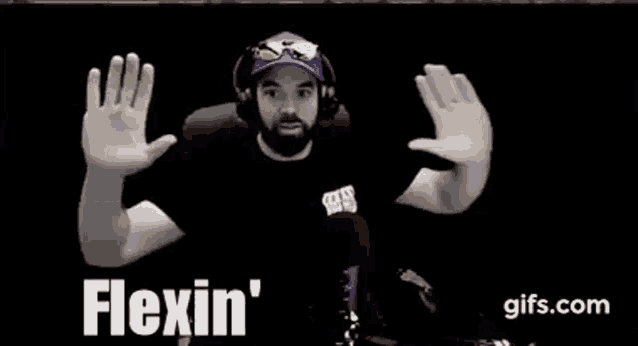 a man with a beard wearing headphones and a hat is making a funny face with his hands .