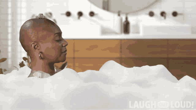 a woman is taking a bath in a bathtub with the words laugh and loud in the corner
