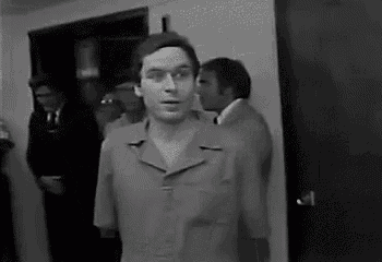a black and white photo of a man in a suit standing in a room .