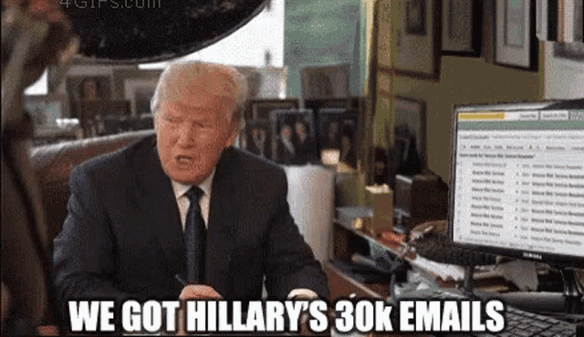 a man in a suit and tie is sitting in front of a computer and says we got hillary 's 30k email