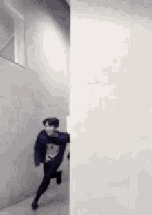 a man in a blue sweater is standing next to a wall and smiling .