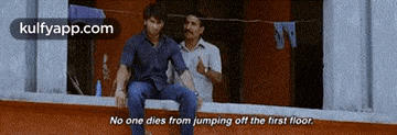 two men are sitting next to each other on a balcony and one of them is talking about jumping off the first floor .