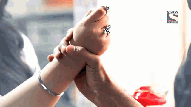 a woman is holding a child 's hand with a sony television logo behind her