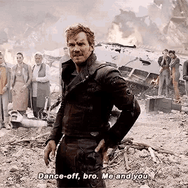 a man in a black jacket stands in front of a group of people and says " dance off bro me and you "