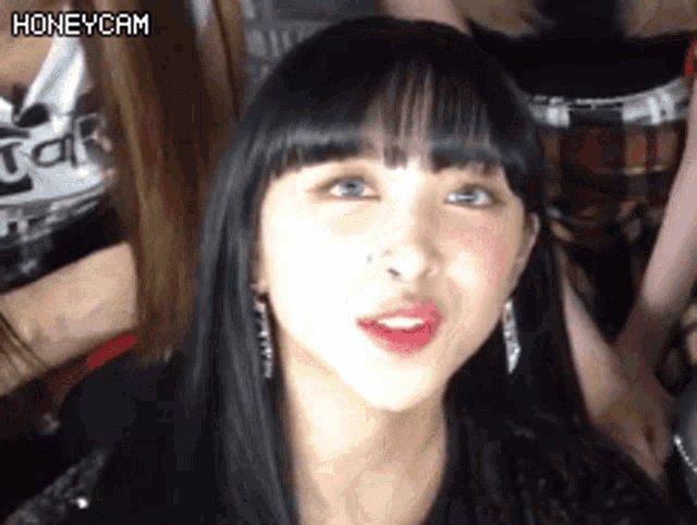 a close up of a woman 's face with long black hair and red lips .