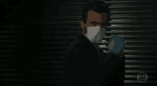 a man wearing a mask and gloves is standing in front of a wall .