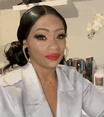 a woman with red lipstick and hoop earrings is wearing a white jacket .