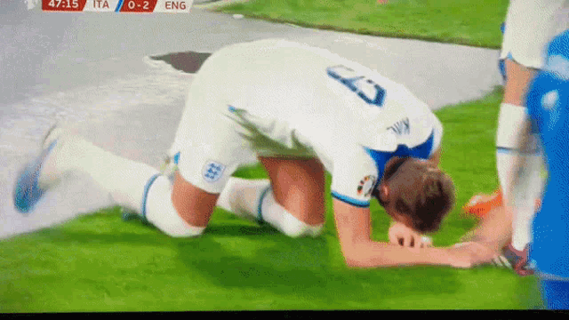 a soccer player with the number 23 on his jersey kneeling on the field