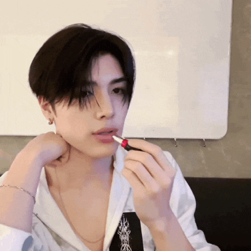 a man is applying red lipstick to his lips while wearing a white shirt