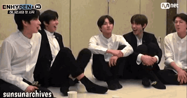 a group of young men are sitting on the floor and laughing