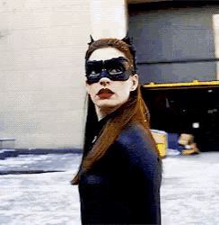 a woman in a catwoman costume is standing in front of a building wearing a mask .