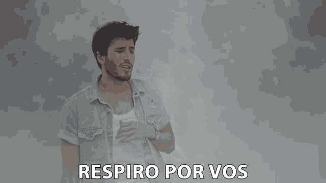 a man in a denim shirt is singing with the words respiro por vos above him