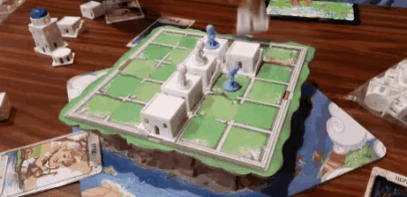 a board game is being played on a wooden table with cards and a map .