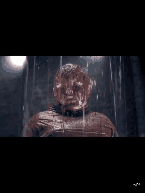a man covered in chocolate is standing in a glass container
