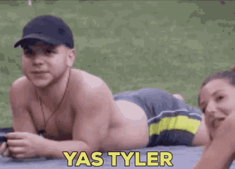 a shirtless man is laying on his stomach next to a woman with the name yas tyler written on the bottom .