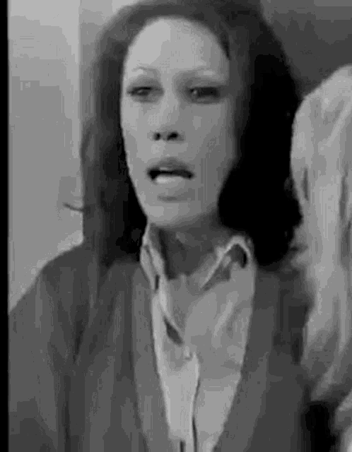 a black and white photo of a woman in a sweater making a face .