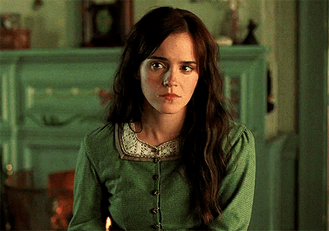 a woman wearing a green shirt with buttons on the front looks at the camera