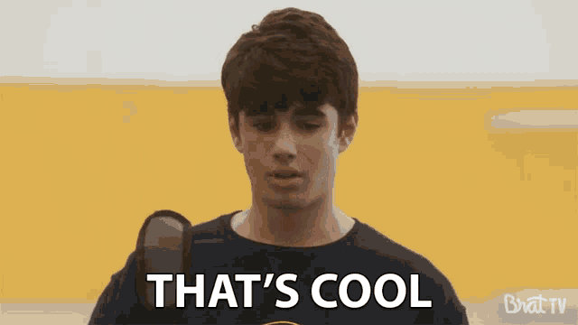 a boy is holding a microphone and saying that 's cool