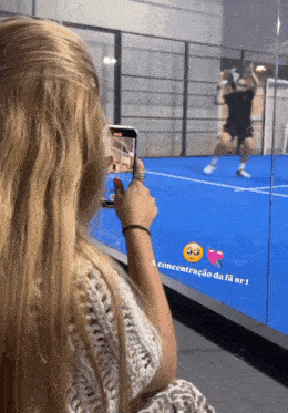 a woman is taking a picture of a man on a tennis court with the words a concentracao da fa nr 1 on the bottom
