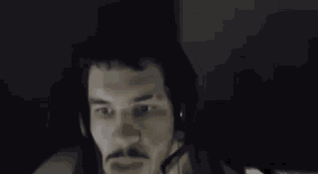 a man with a mustache is wearing a headset and talking into a microphone .