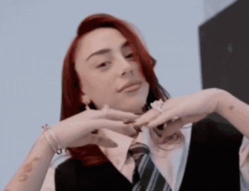 a woman with red hair is wearing a black vest and a tie