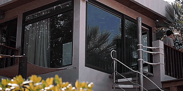 a man stands on a balcony looking out a window