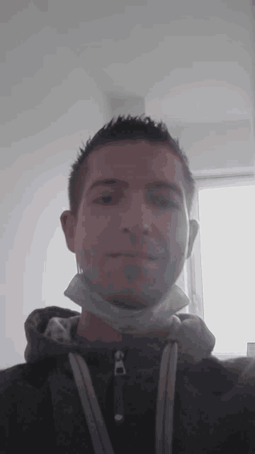 a man wearing a hoodie and a face mask smiles for the camera
