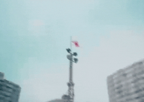 a very tall tower with a flag on top of it flying in the wind .