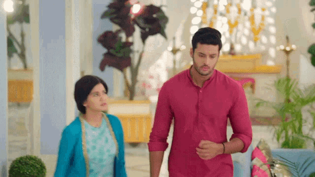 a man in a pink shirt is walking next to a woman in a blue dress