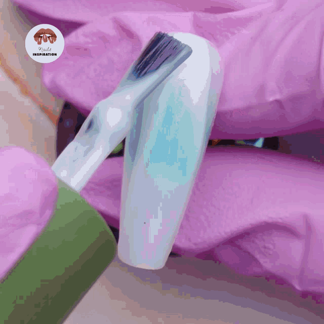 a brush is being used to paint a nail with a pink glove behind it that says nails inspiration
