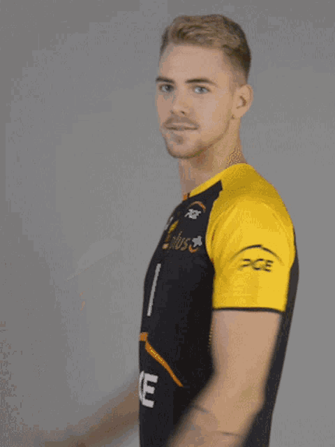 a man wearing a black and yellow shirt with the word e on it