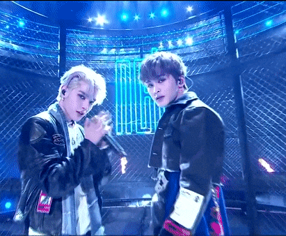 two young men are standing next to each other on a stage holding microphones .