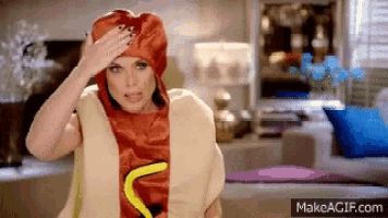 a woman is wearing a hot dog costume and covering her head with her hand .