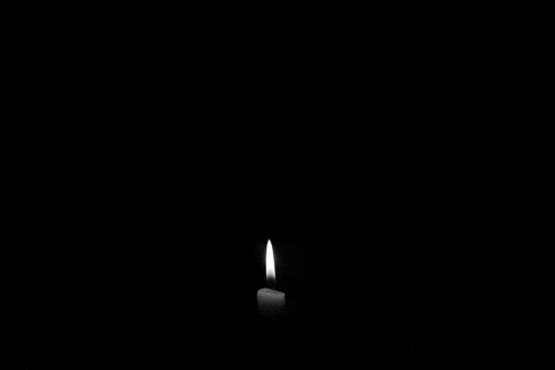 a candle is lit in the dark with a flame coming out of it .