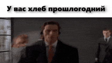 a man in a suit and tie is wearing headphones while another man stands in the background ..