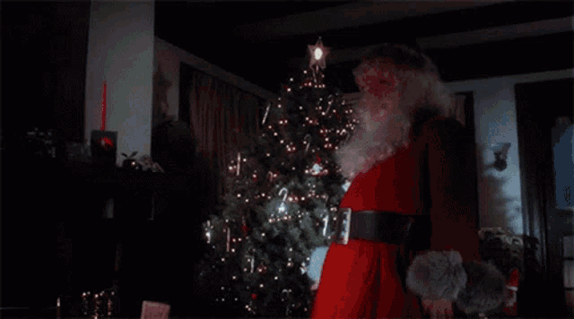 a santa claus holding a knife in front of a christmas tree