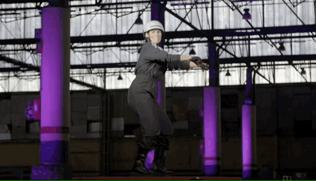 a person wearing a helmet is standing in a warehouse with purple lights