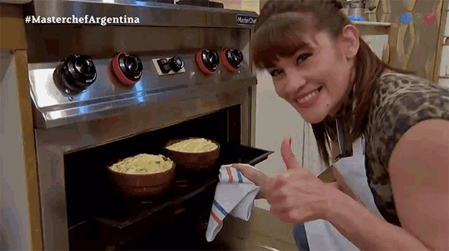 a woman is giving a thumbs up in front of a master chef oven