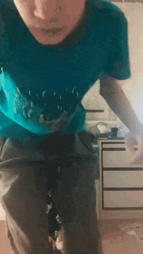 a man in a blue shirt is standing in front of a cabinet