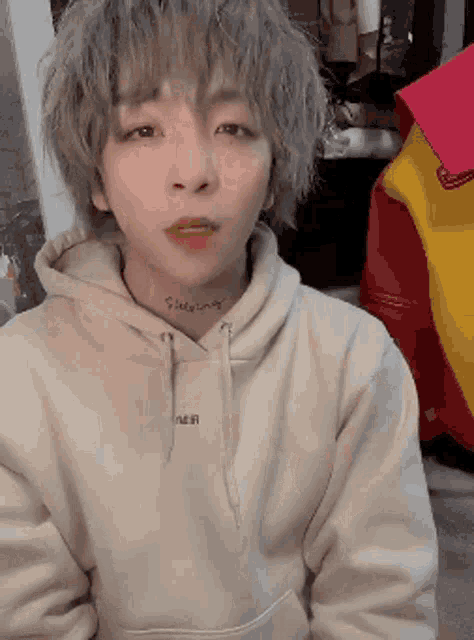 a young man with a tattoo on his neck is wearing a hoodie
