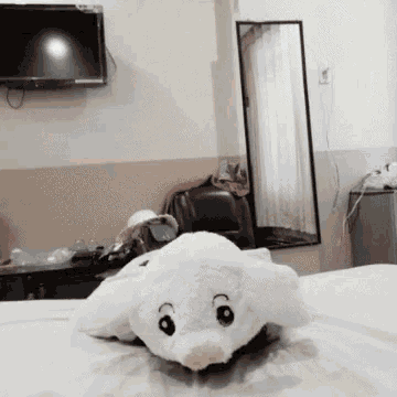 a stuffed animal is laying on a bed in front of a flat screen tv