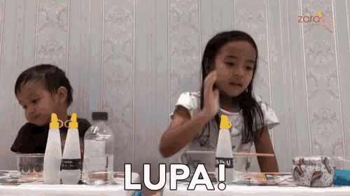 a boy and a girl are sitting at a table with bottles of glue and the word lupa written on the table