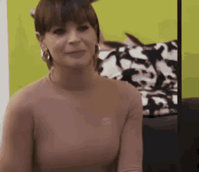 a woman in a pink shirt and earrings is sitting on a couch .