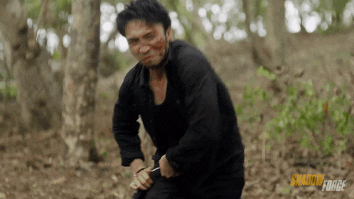 a man in a black shirt is holding a knife in the woods with the words shadow force on the bottom