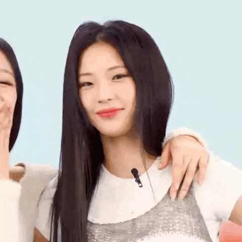 a woman with long black hair is holding another woman 's arm and smiling .