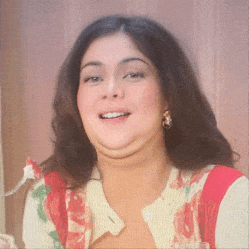 a woman wearing a floral cardigan and earrings smiles