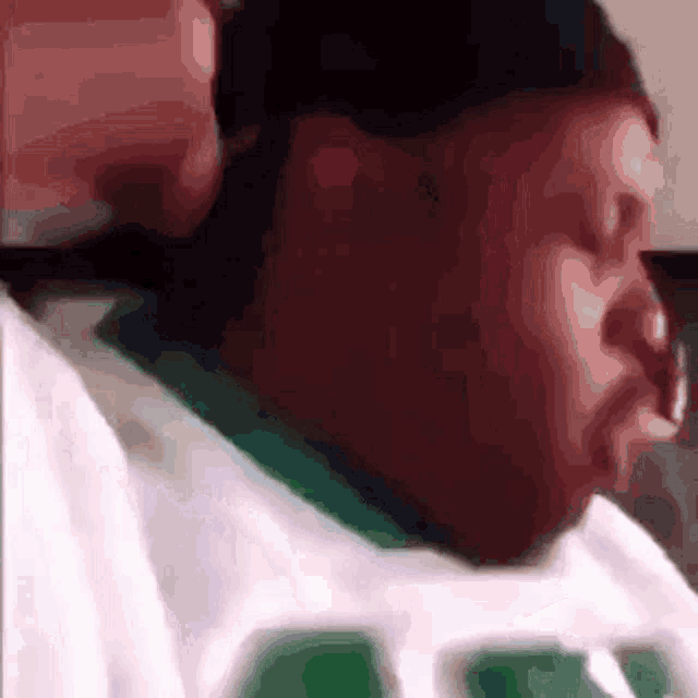 a close up of a man wearing a green and white shirt with the letter c on it