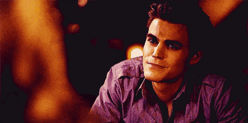 a man in a purple shirt is smiling while looking at another man .